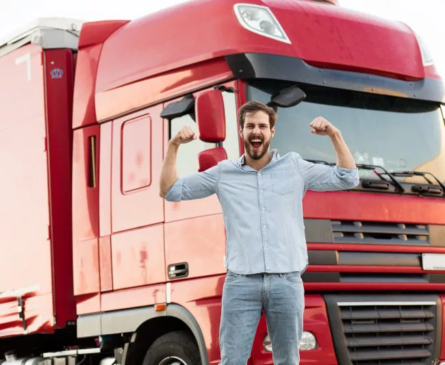 strong masculine truck driver standing outside and showing his muscle with his vehicle behind